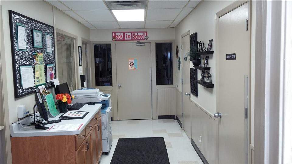 A hallway with a front desk, a bulletin board, and a "Back to School!" sign above a door