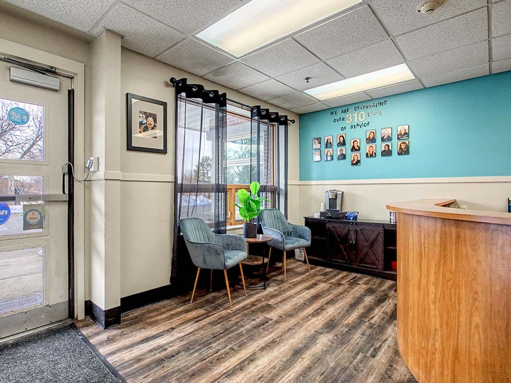 Lobby waiting area with a reception desk, chairs, and a photo wall