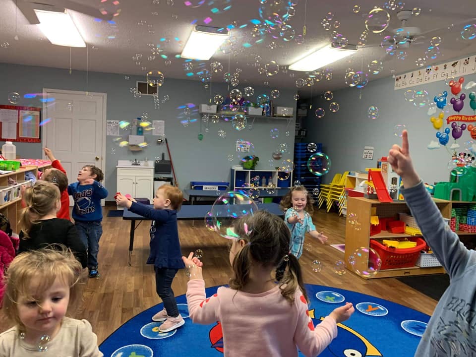 Children playing with bubbles in a classroom
