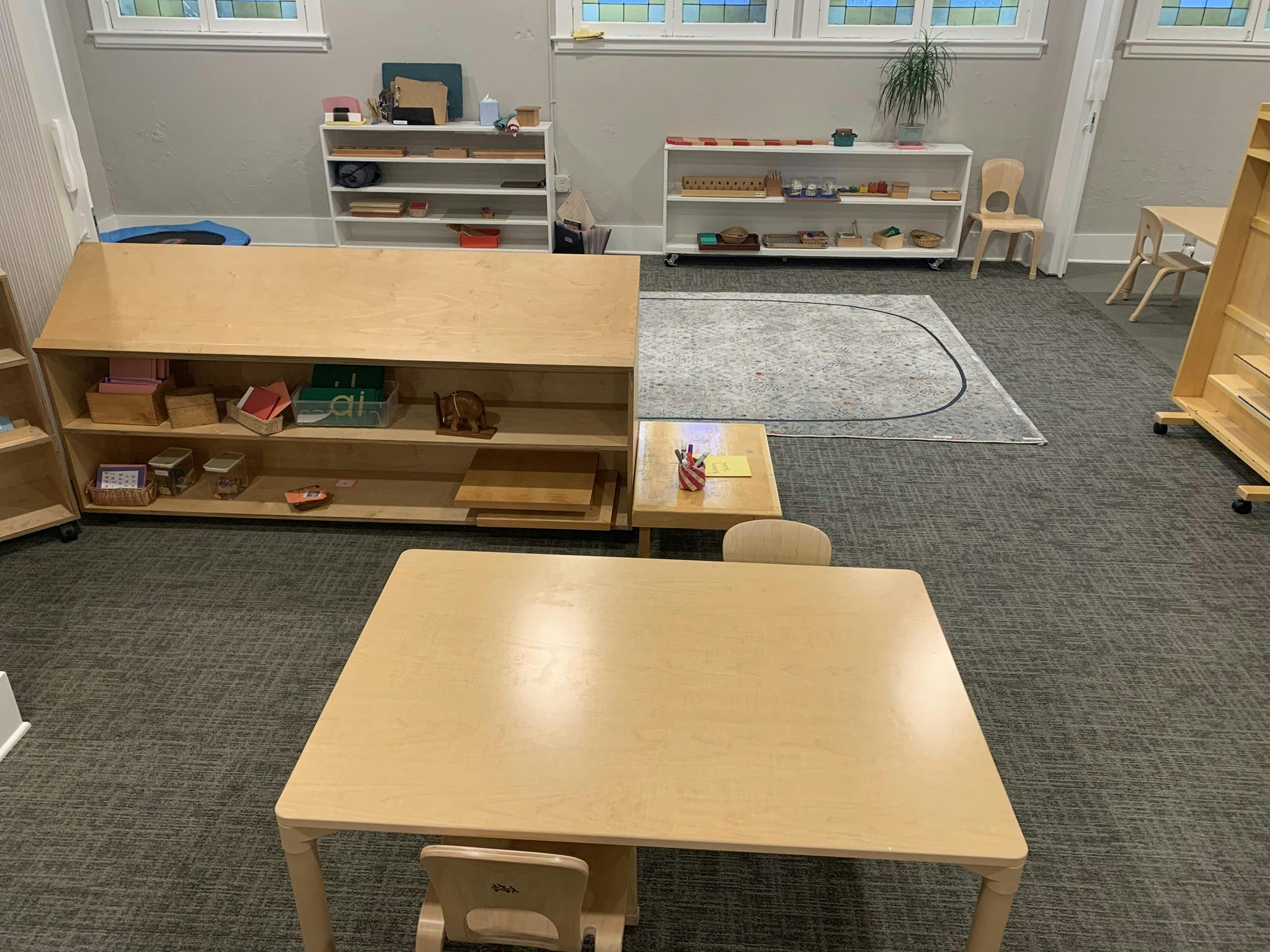 Classroom with wooden shelves, tables, and chairs