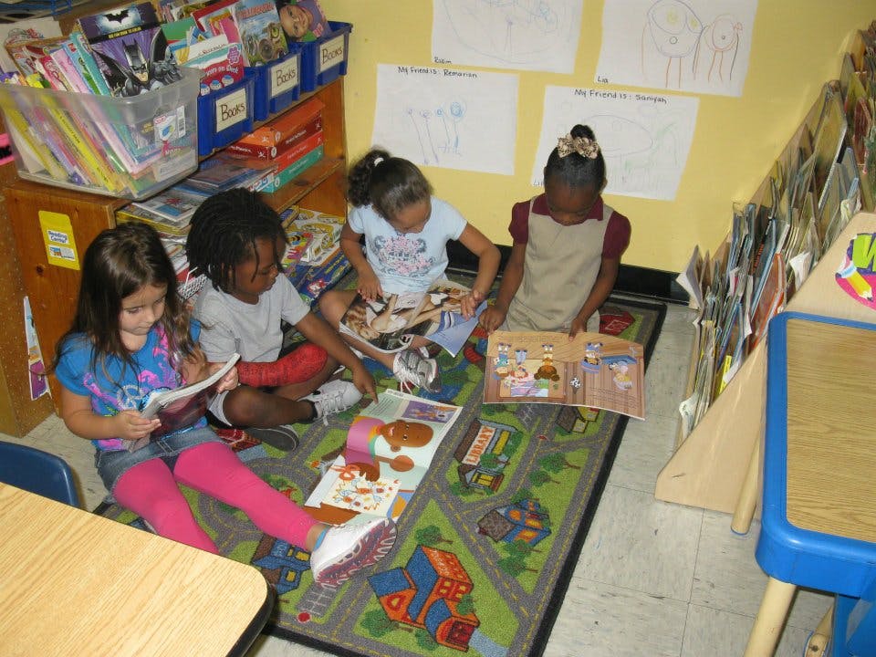 Four children sitting on a rug reading books