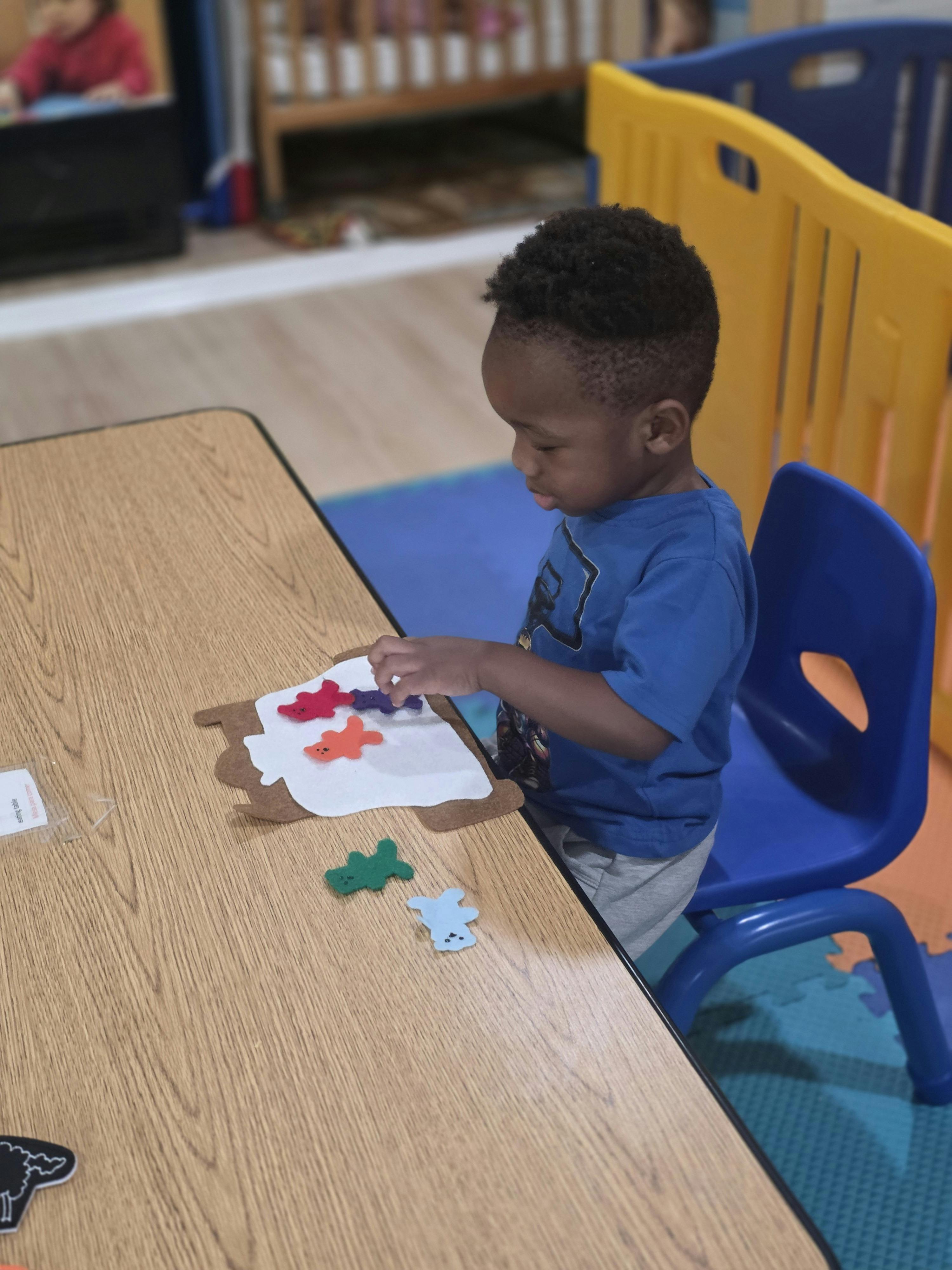 Child placing felt shapes on a board at a table