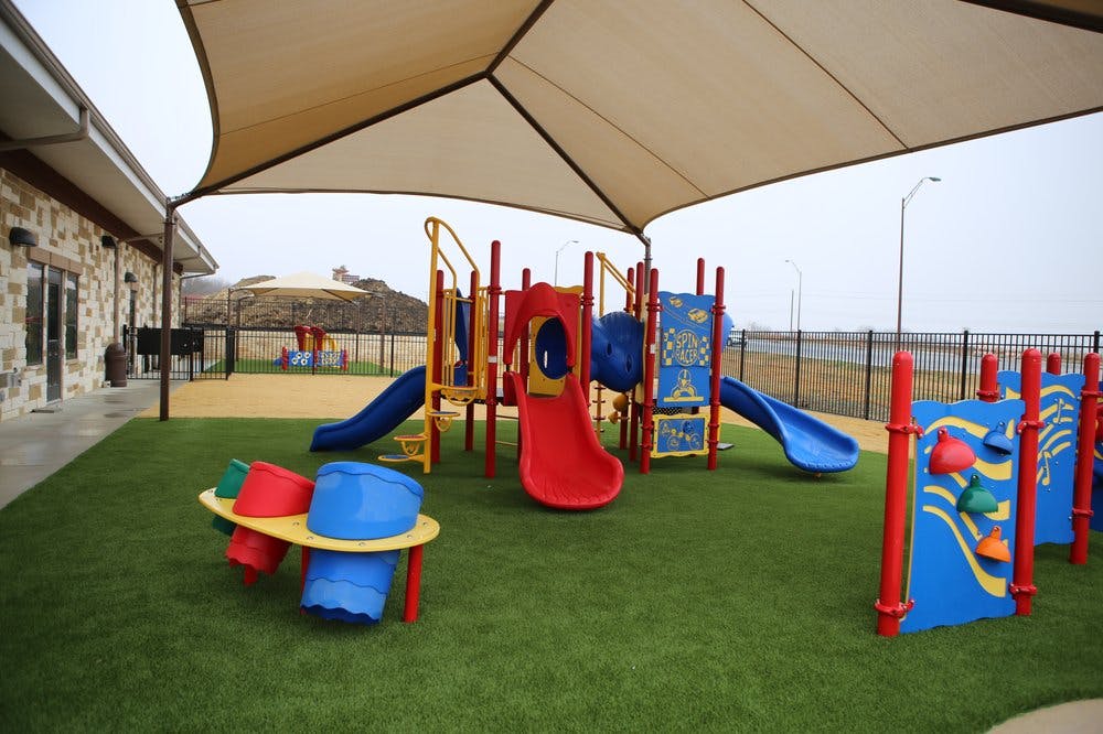 Playground with slides and climbing structures under a large shade