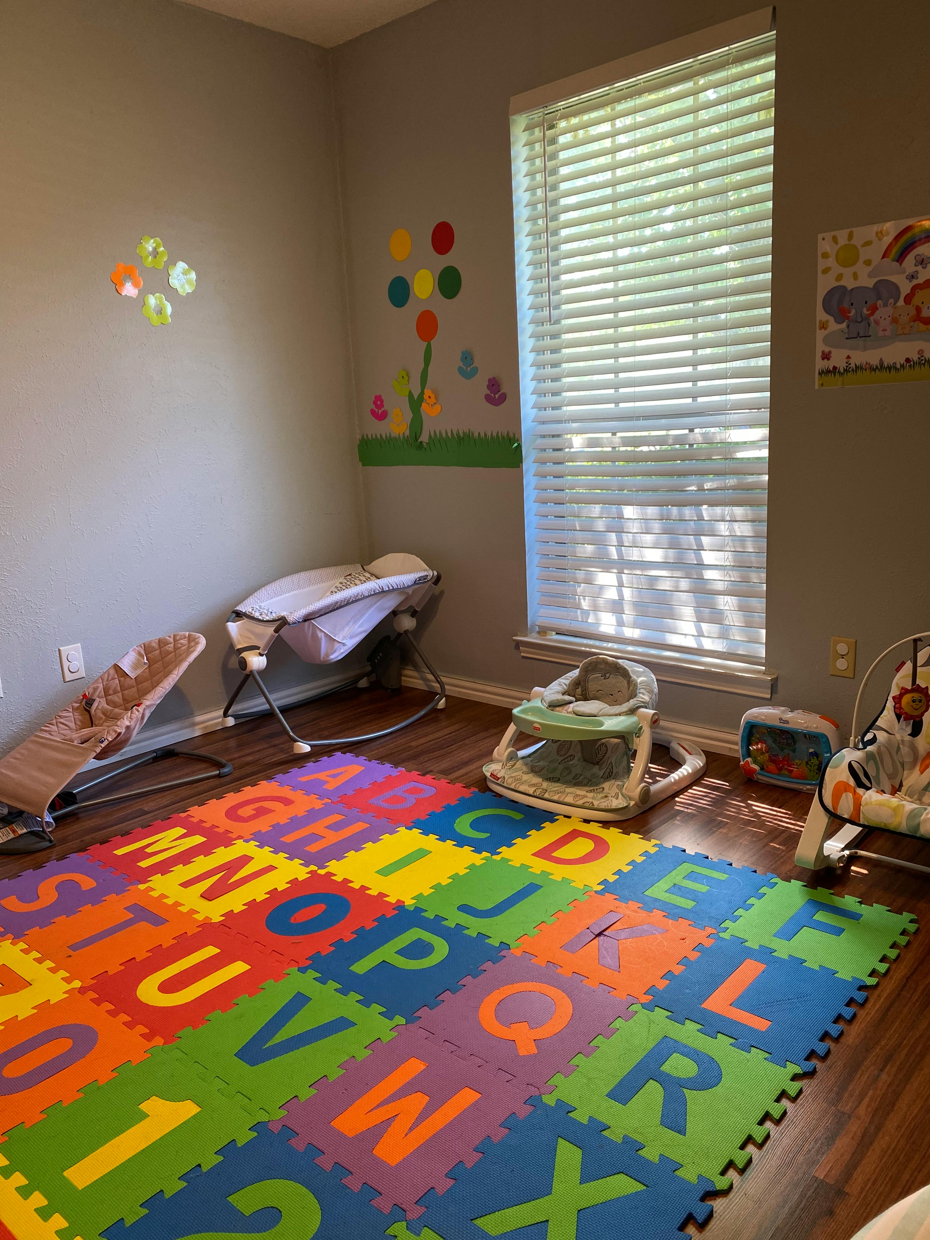 Nursery room with a colorful alphabet play mat and baby equipment