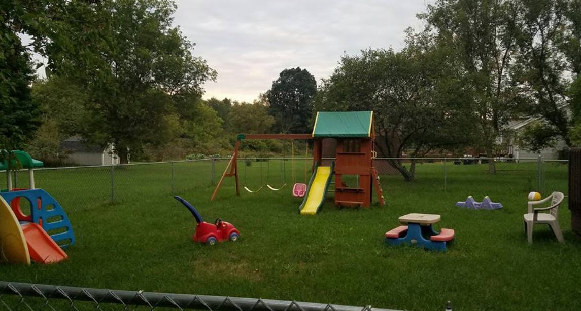 Playground with swings, slide, and small table in a grassy yard