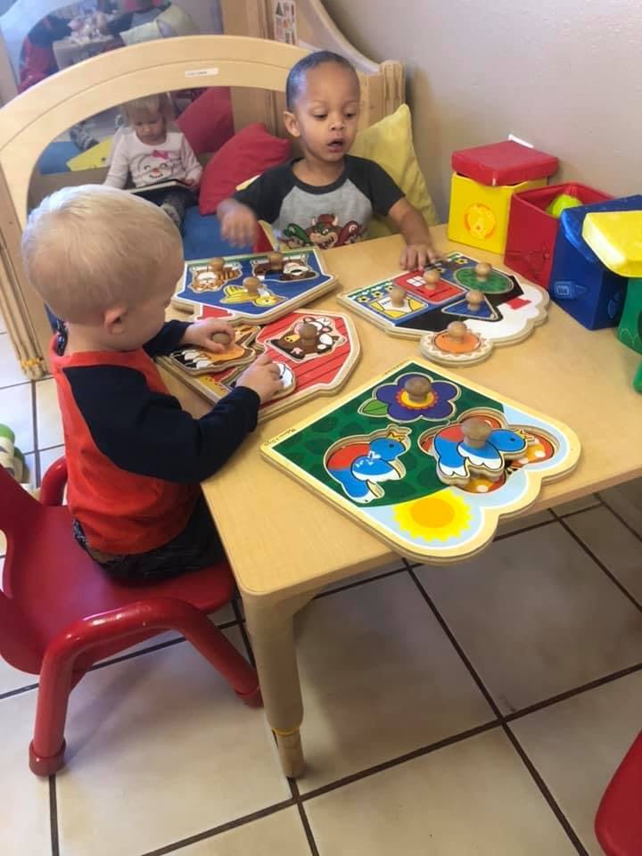 Two children playing with puzzles at a table