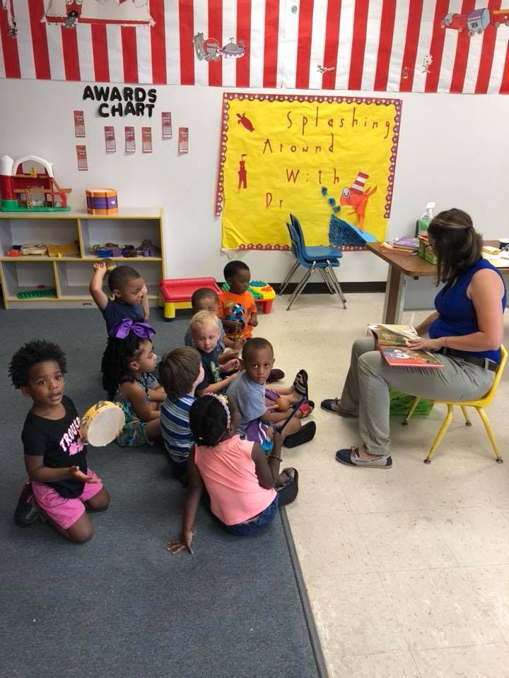 Adult reading to a group of children in a classroom