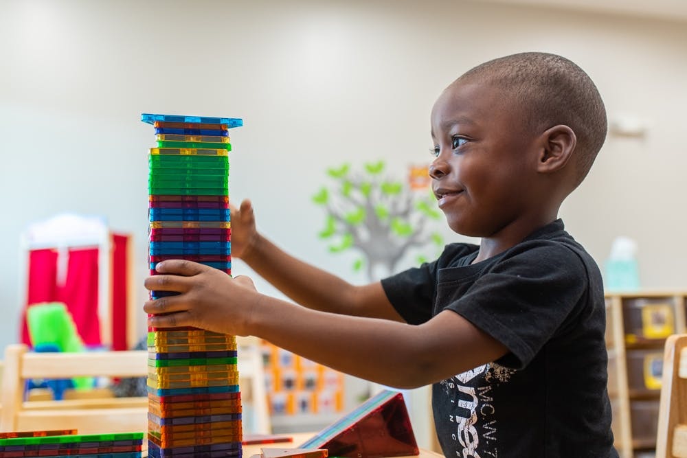 Child building a tall structure with colorful blocks