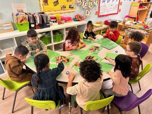 Children sitting around a table doing an art activity in a classroom