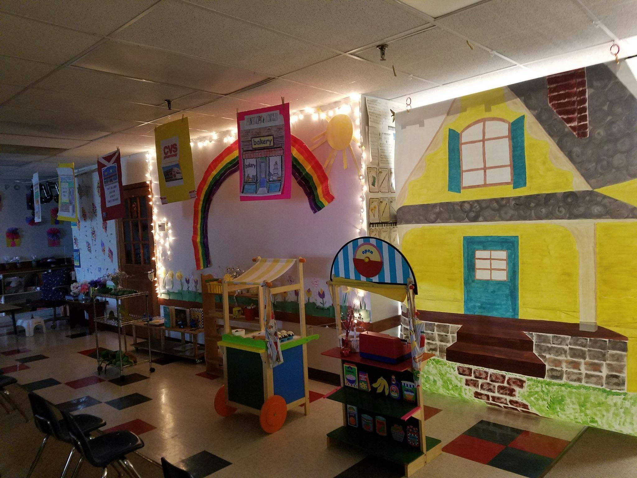 Classroom with a rainbow decoration and a yellow house mural