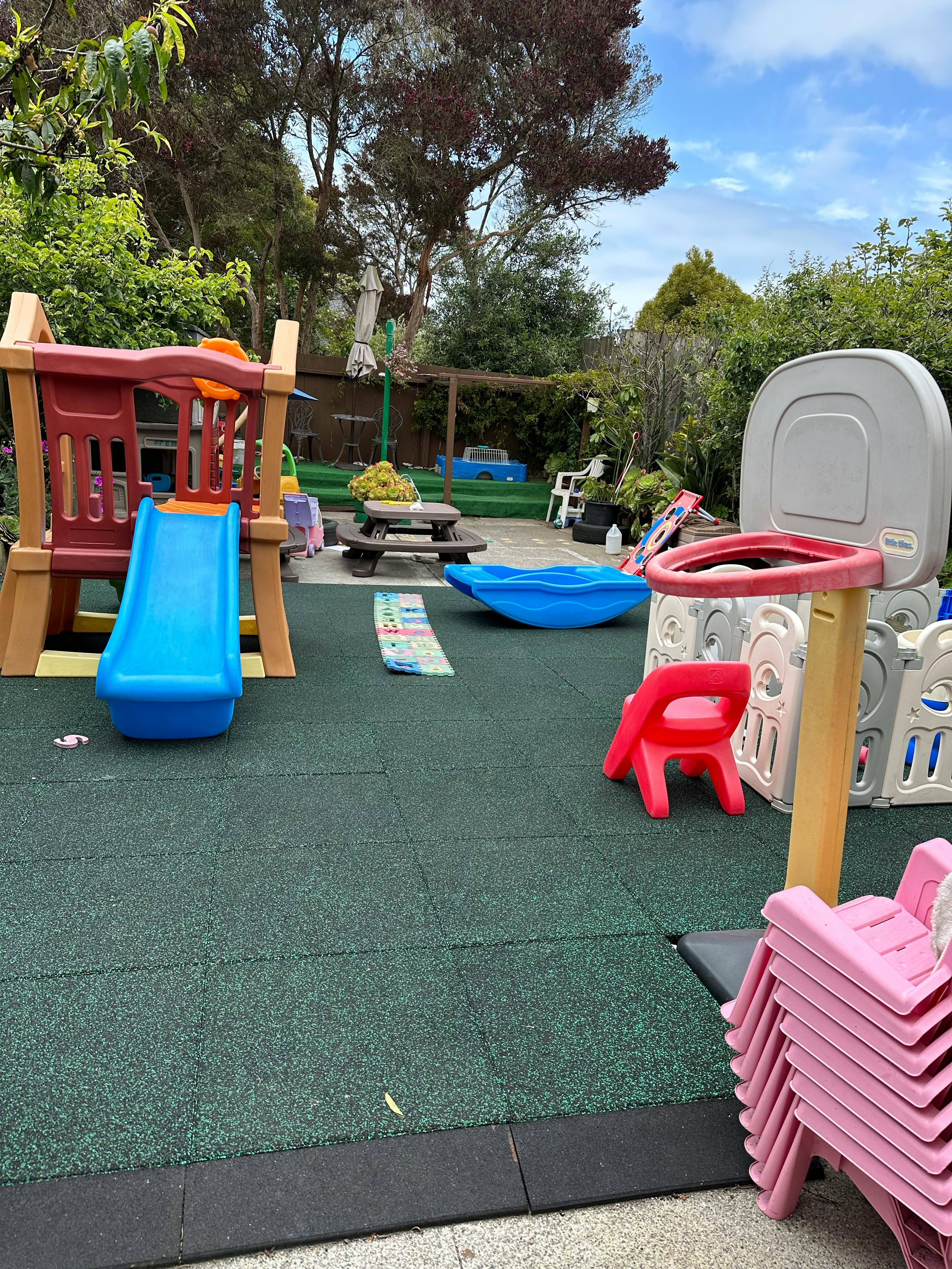 Outdoor playground with slide, picnic table, and basketball hoop