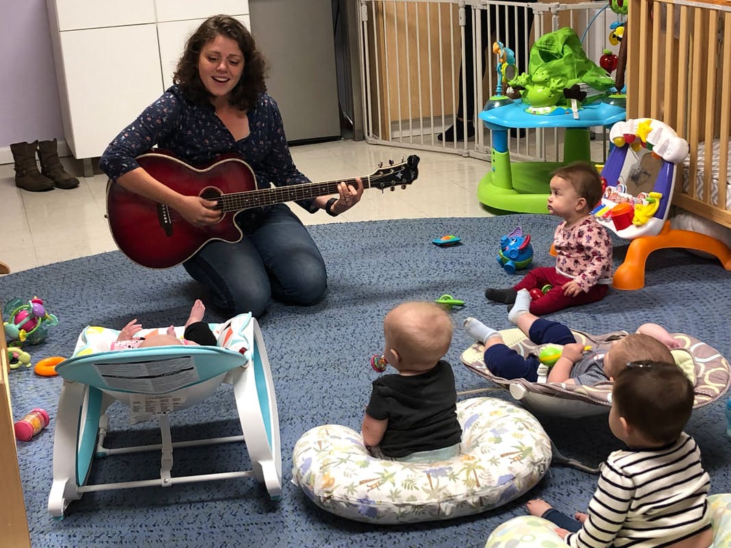 Person playing guitar for multiple babies and children