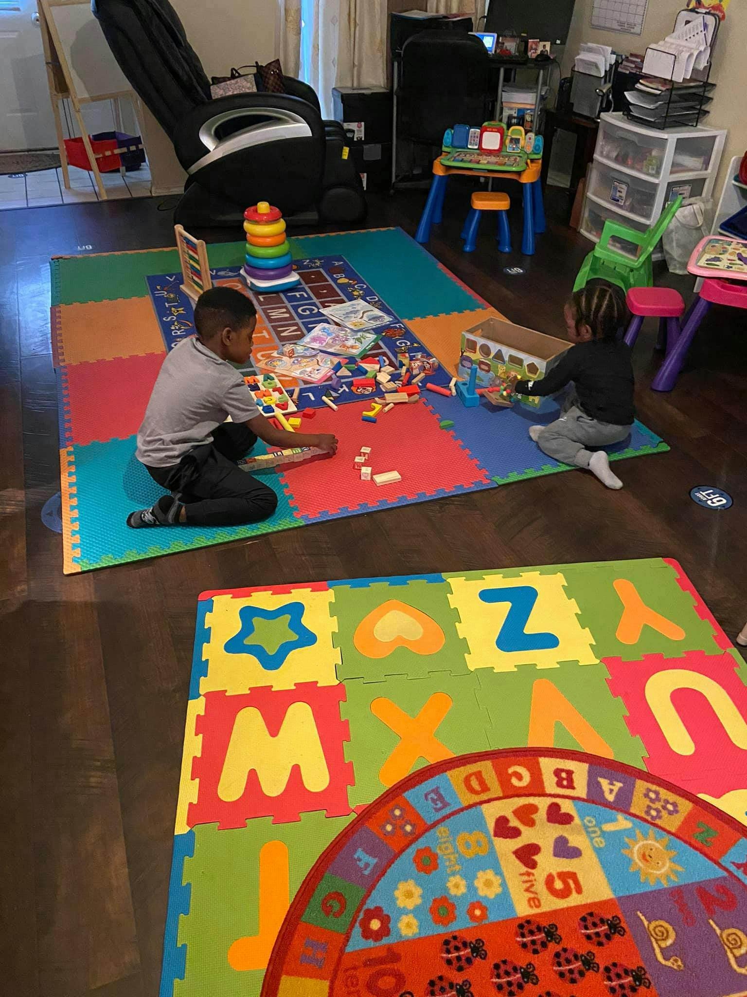 Two children playing with toys on a colorful mat