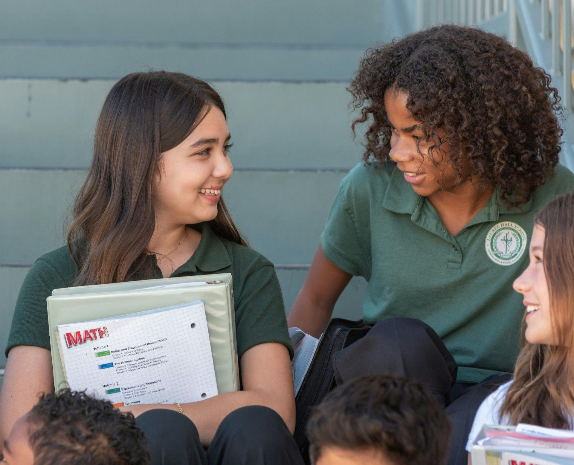 two teens in school uniforms discussing a math textbook