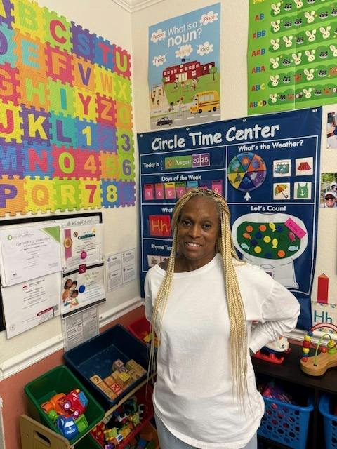 Person standing in a classroom with educational wall charts and toys