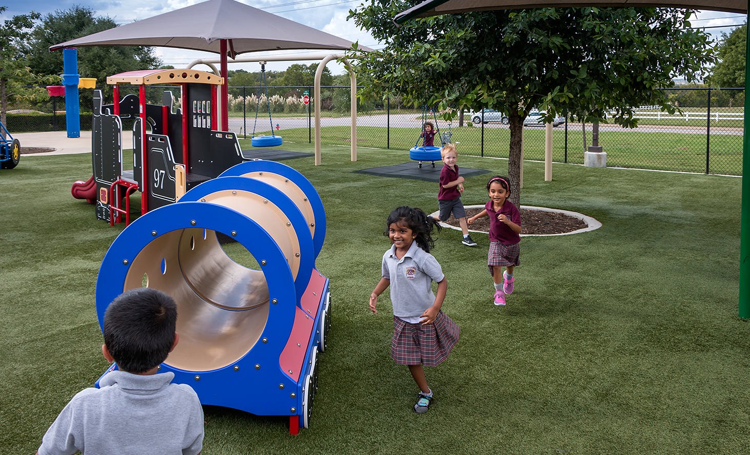 Children playing on a playground with a tunnel and play structure