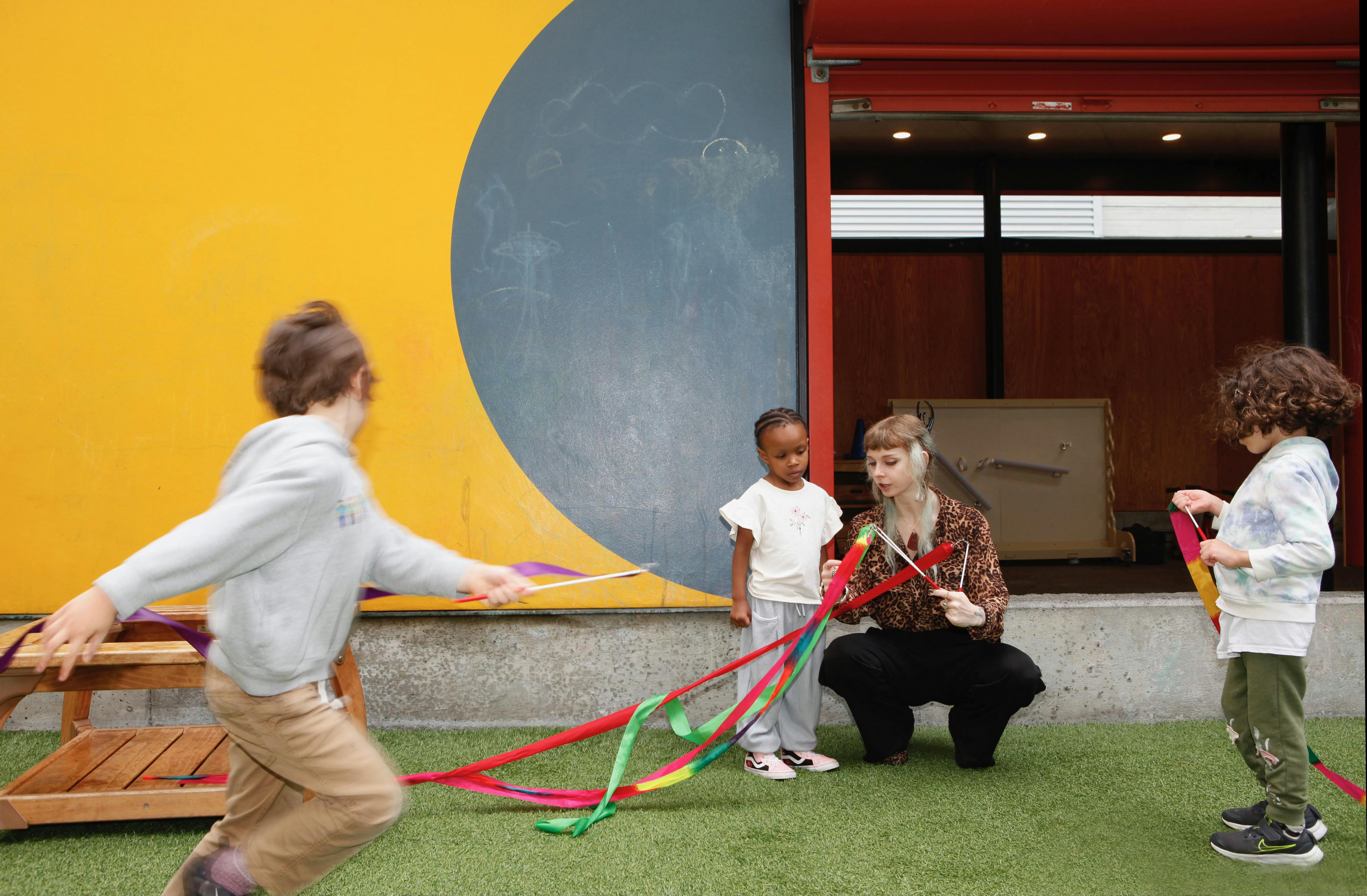 Person and children playing with colorful ribbons outdoors