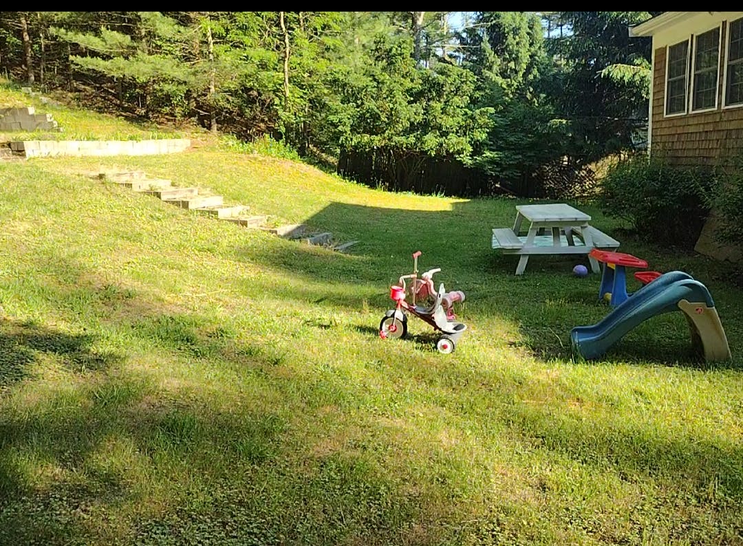 Tricycle and slide on a grassy lawn with a picnic table
