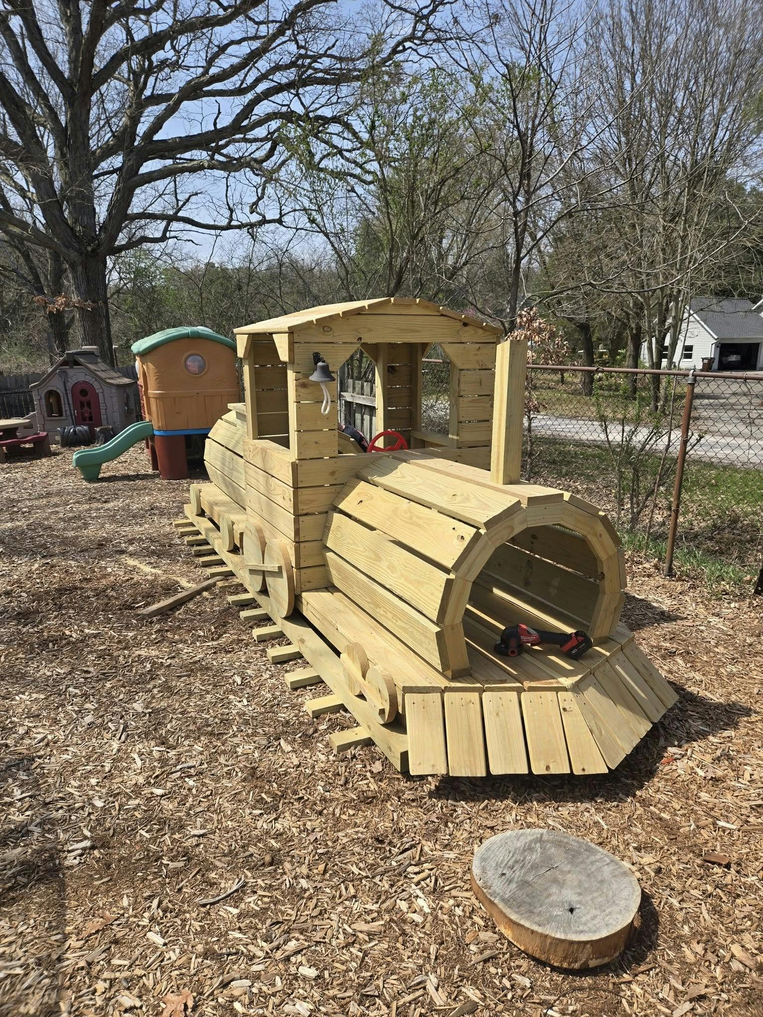 Wooden train play structure on wood chips