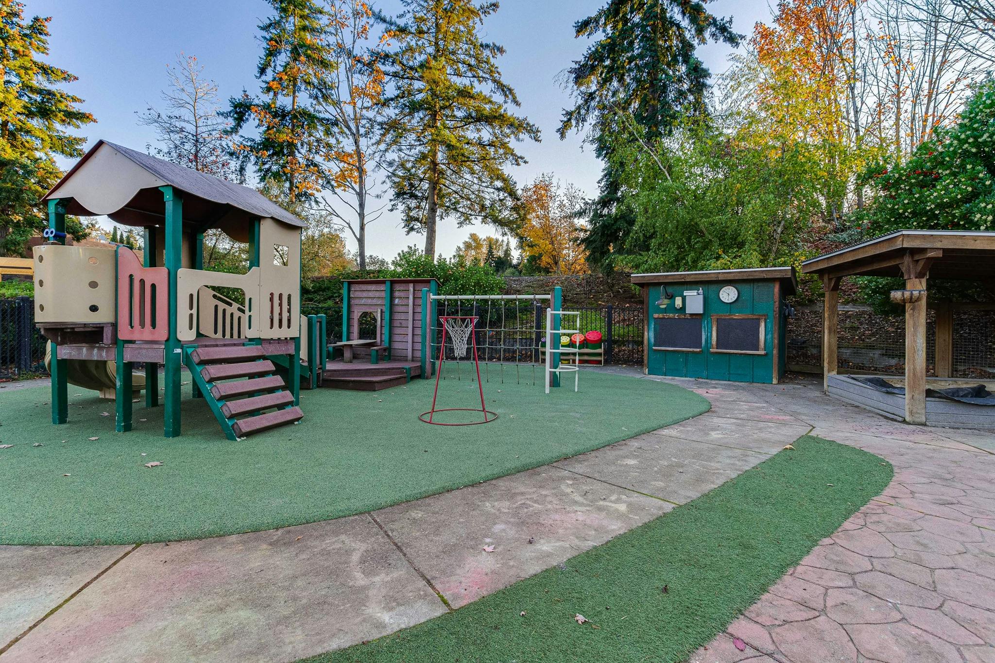 Outdoor playground with play structure, swings, and green turf