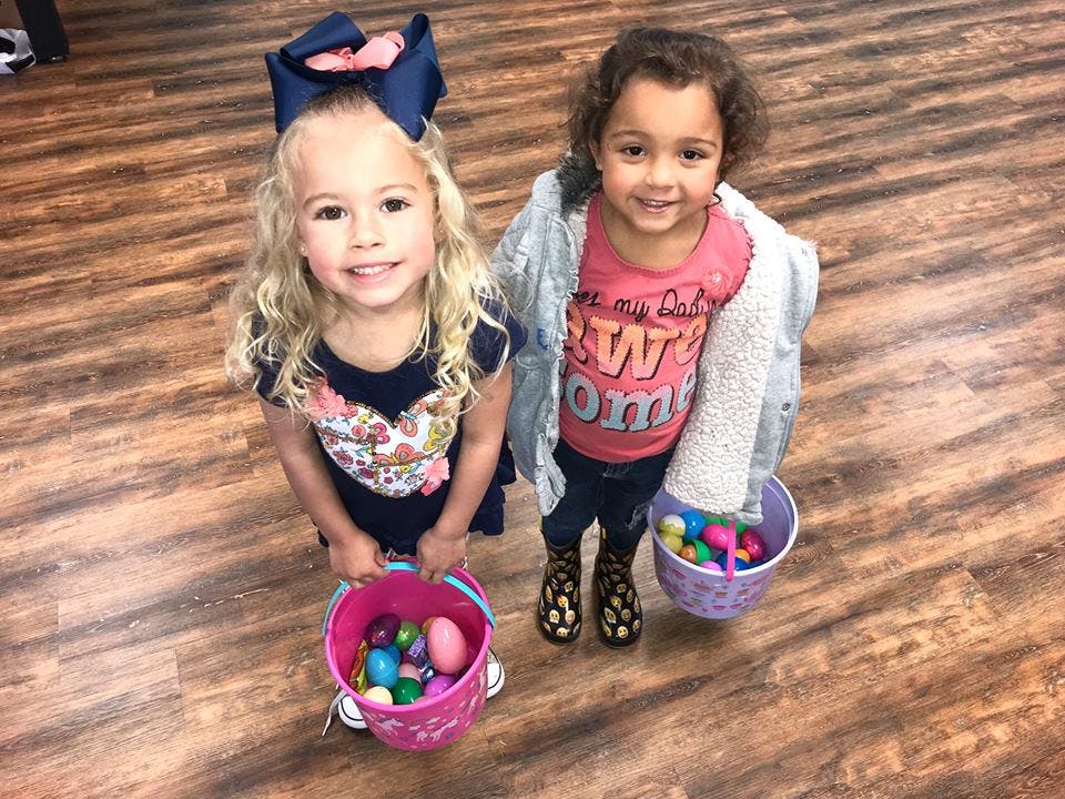 Two children holding buckets filled with colorful eggs