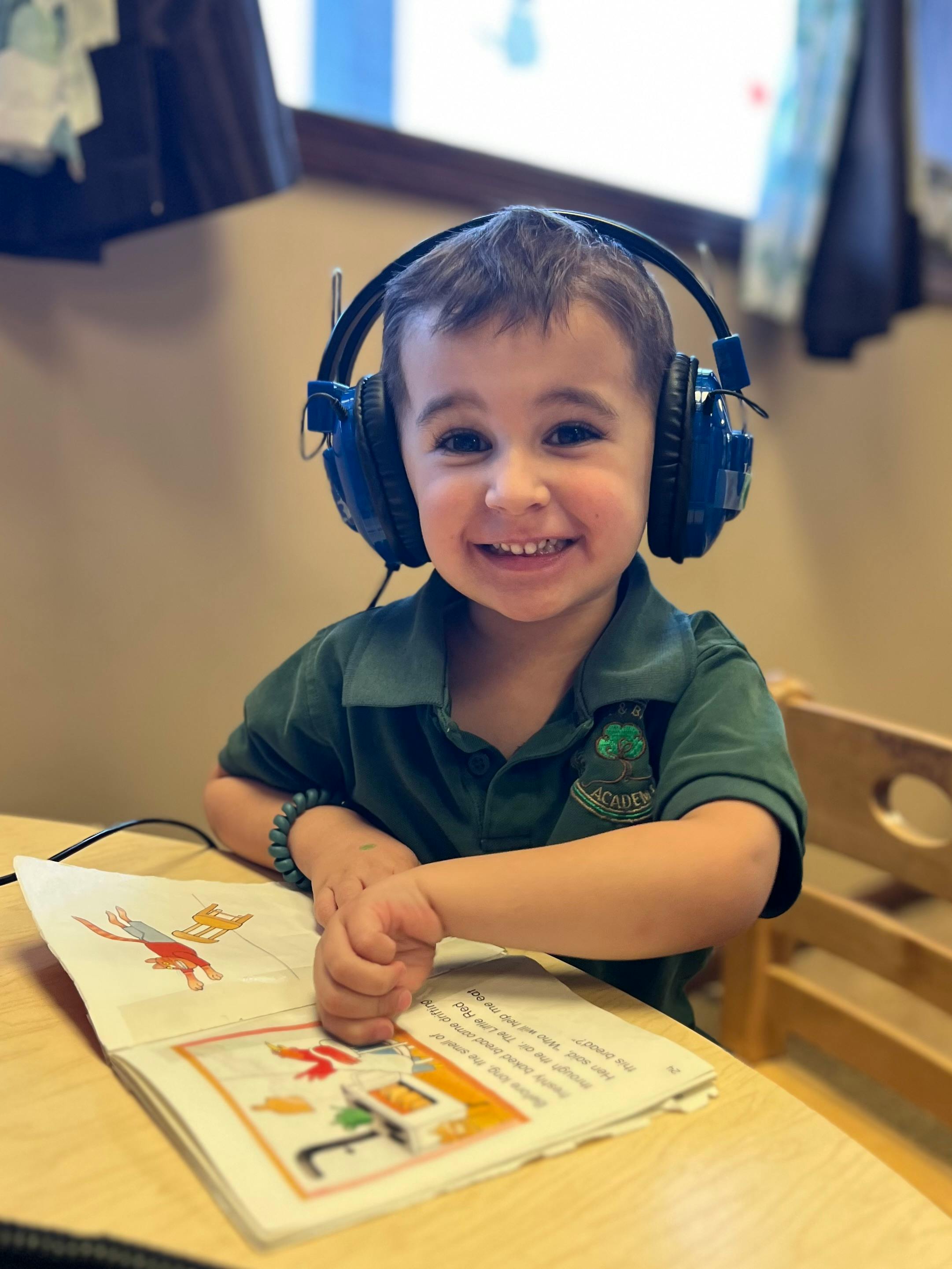 Child wearing headphones and looking at an open book
