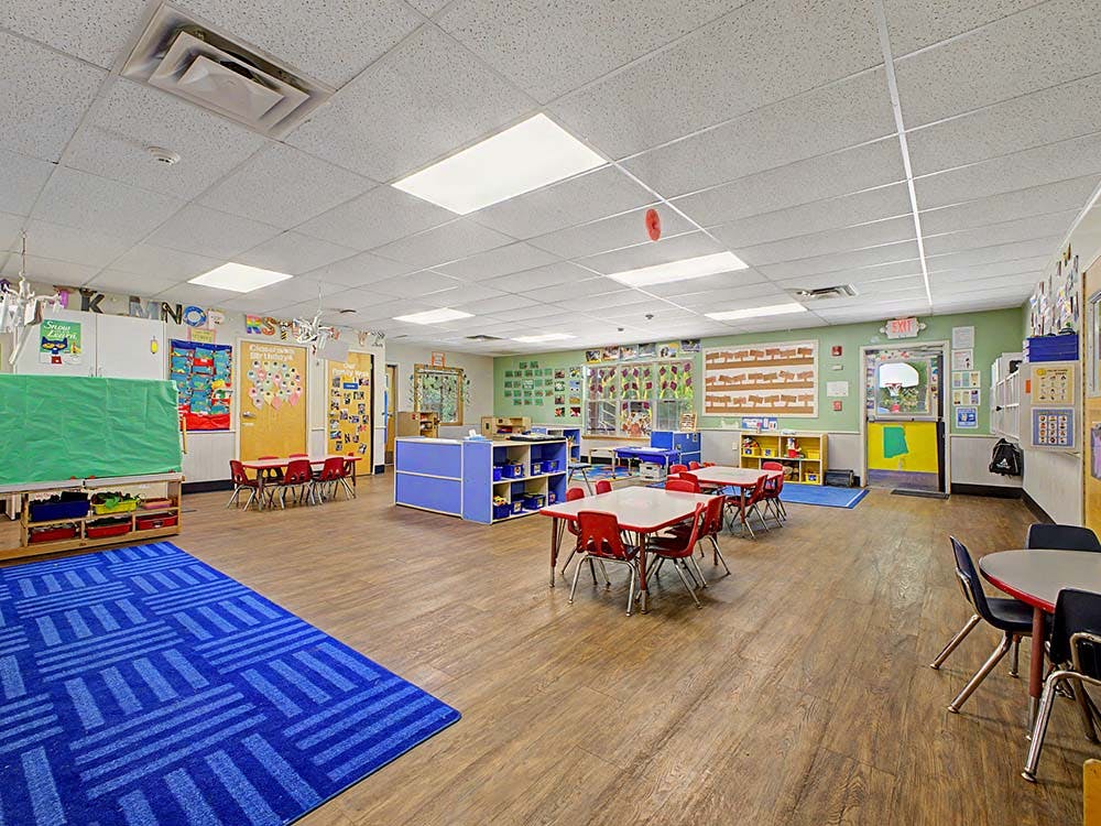 Empty colorful preschool classroom with small tables and chairs