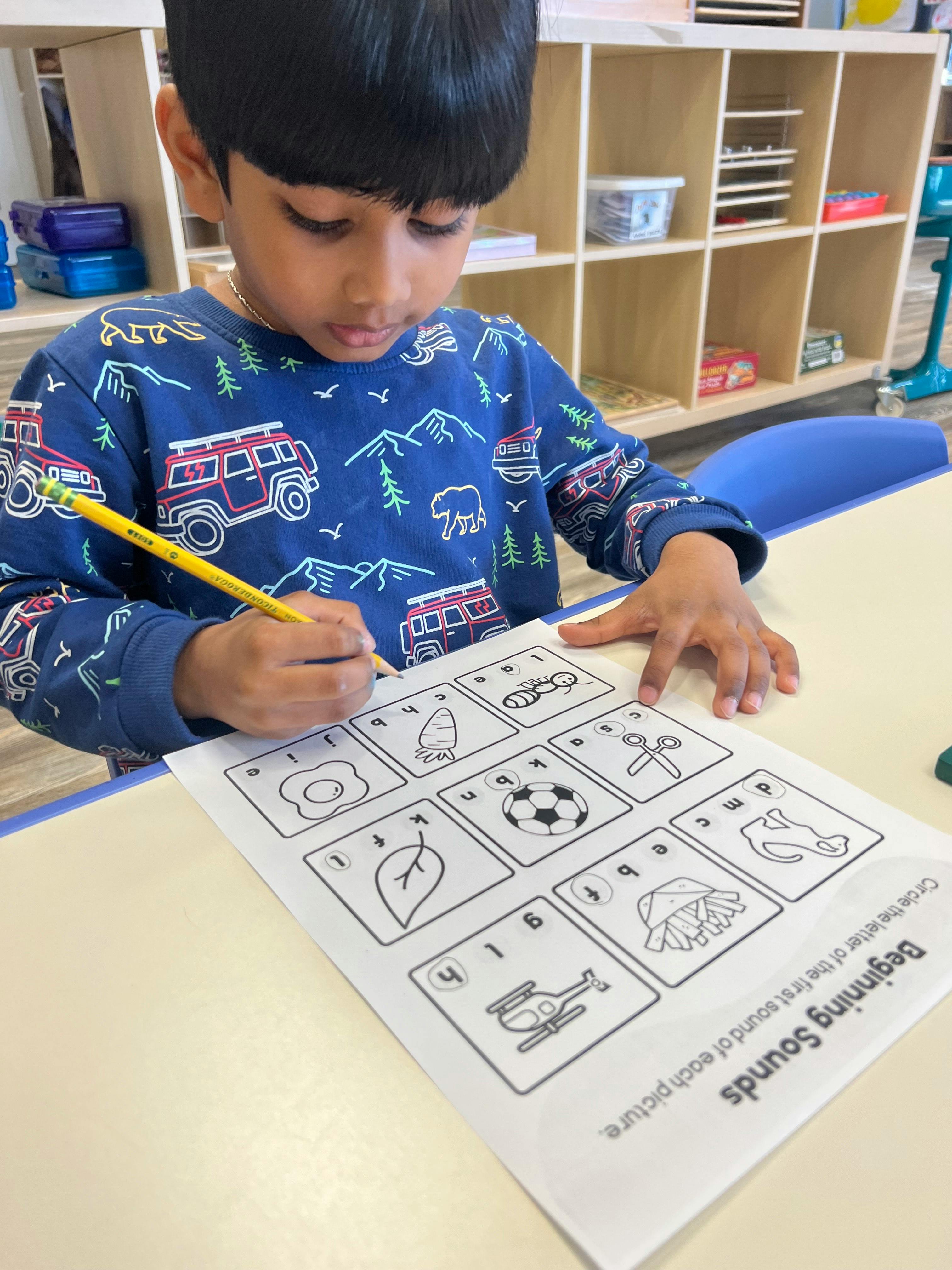 Child writing on a worksheet with a pencil