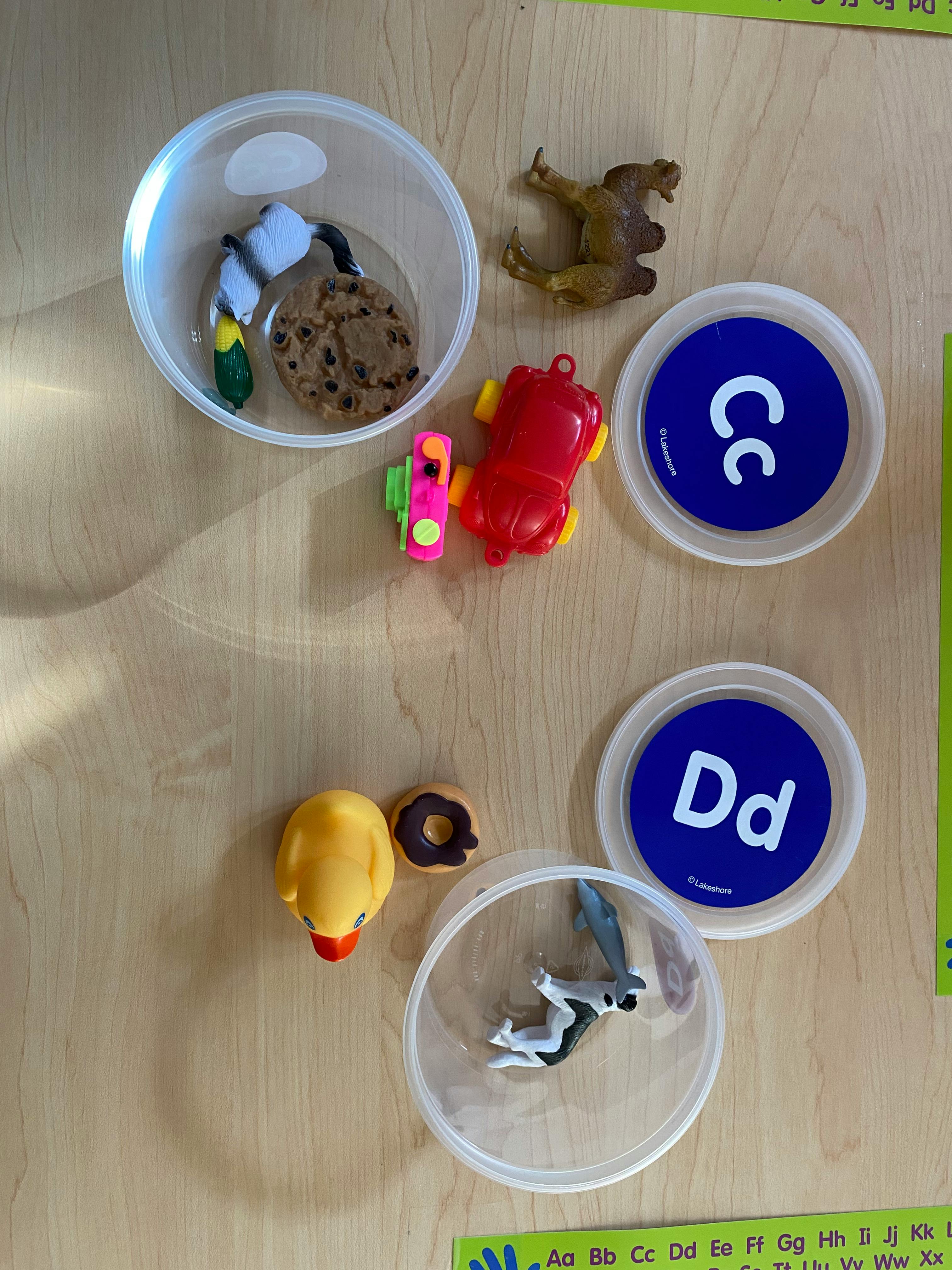 Various small toys and alphabet letter discs on a wooden surface