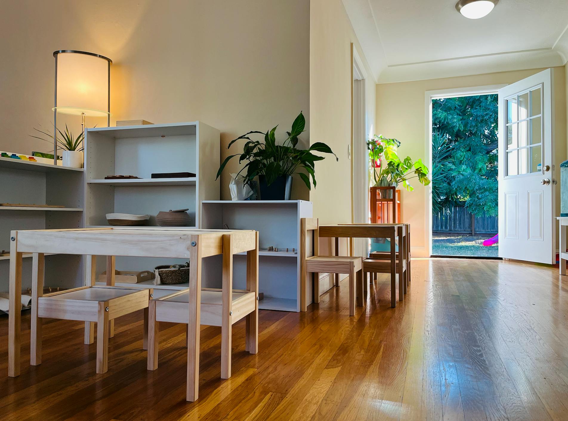 Small wooden tables and chairs in a room with an open door to outside