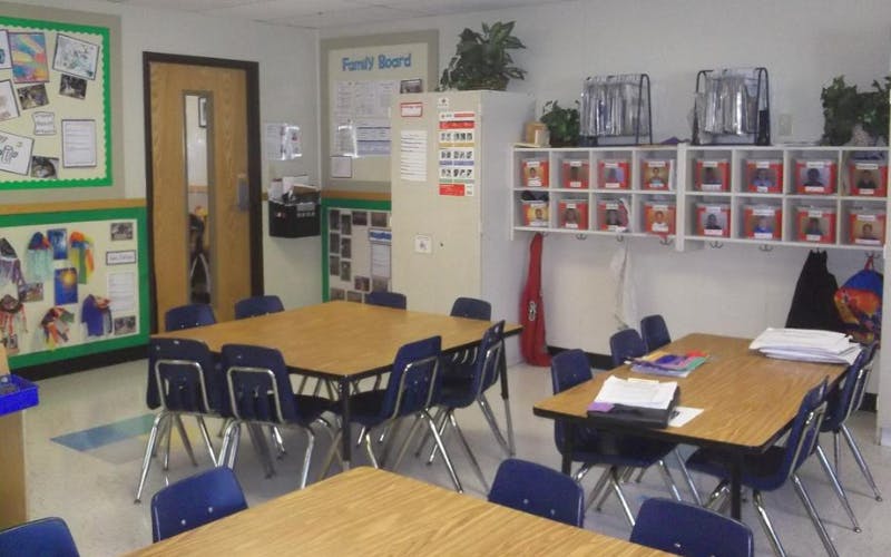 Empty classroom with student tables and chairs, cubbies, and bulletin boards