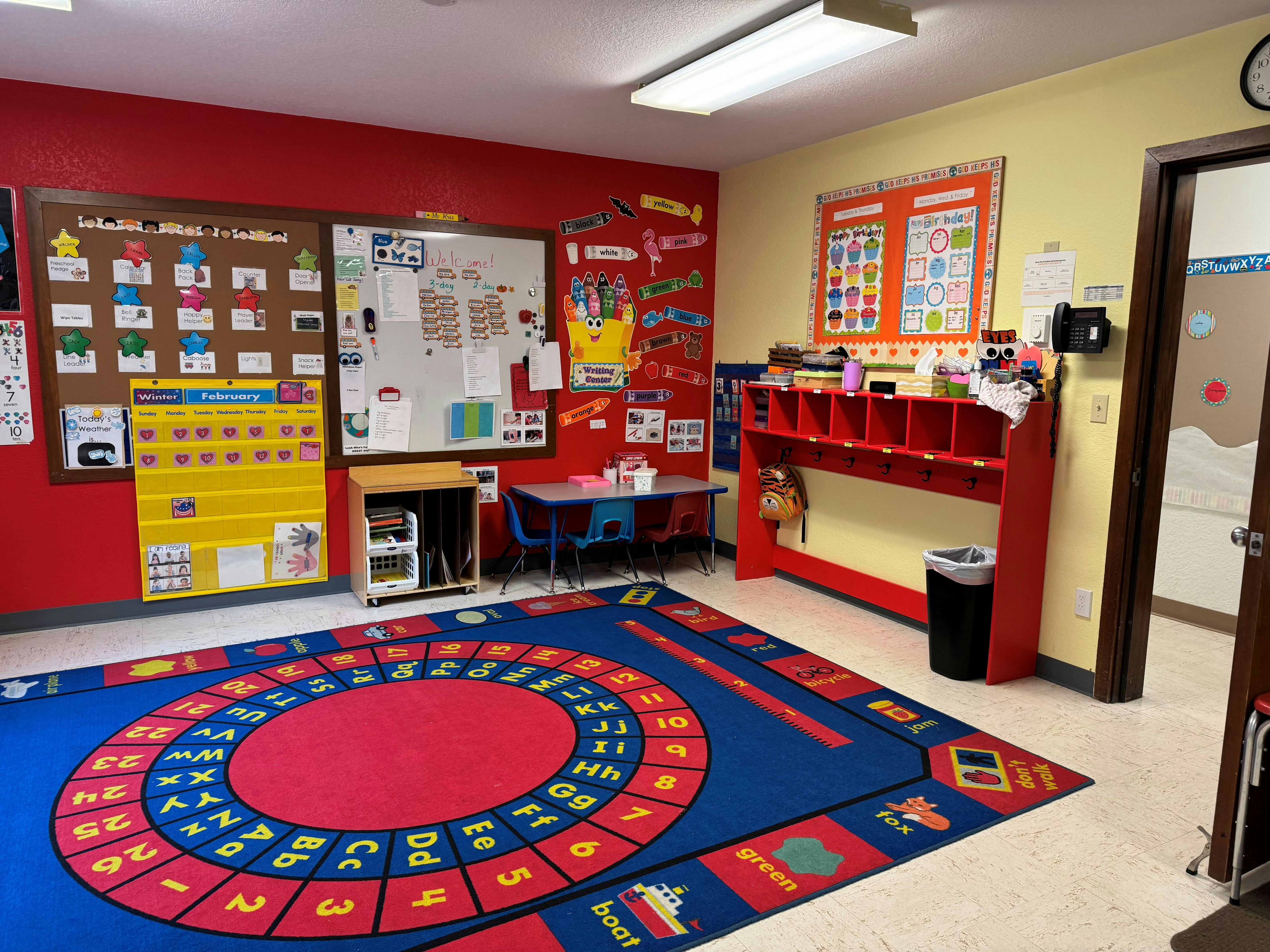 Colorful classroom with a large alphabet rug, small tables, and bulletin boards