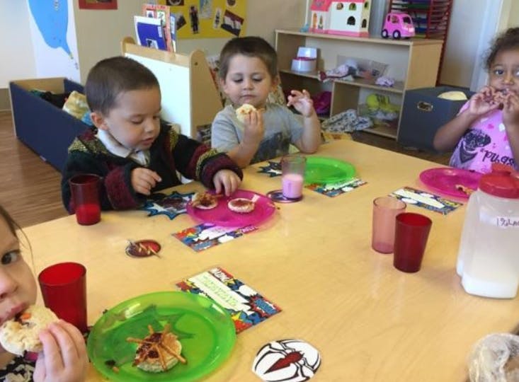 Children eating snacks at a table in a classroom