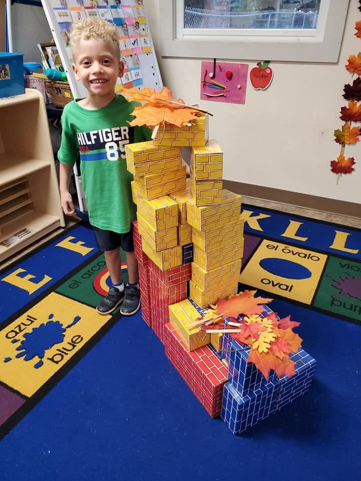 Child standing next to a tall structure made of blocks