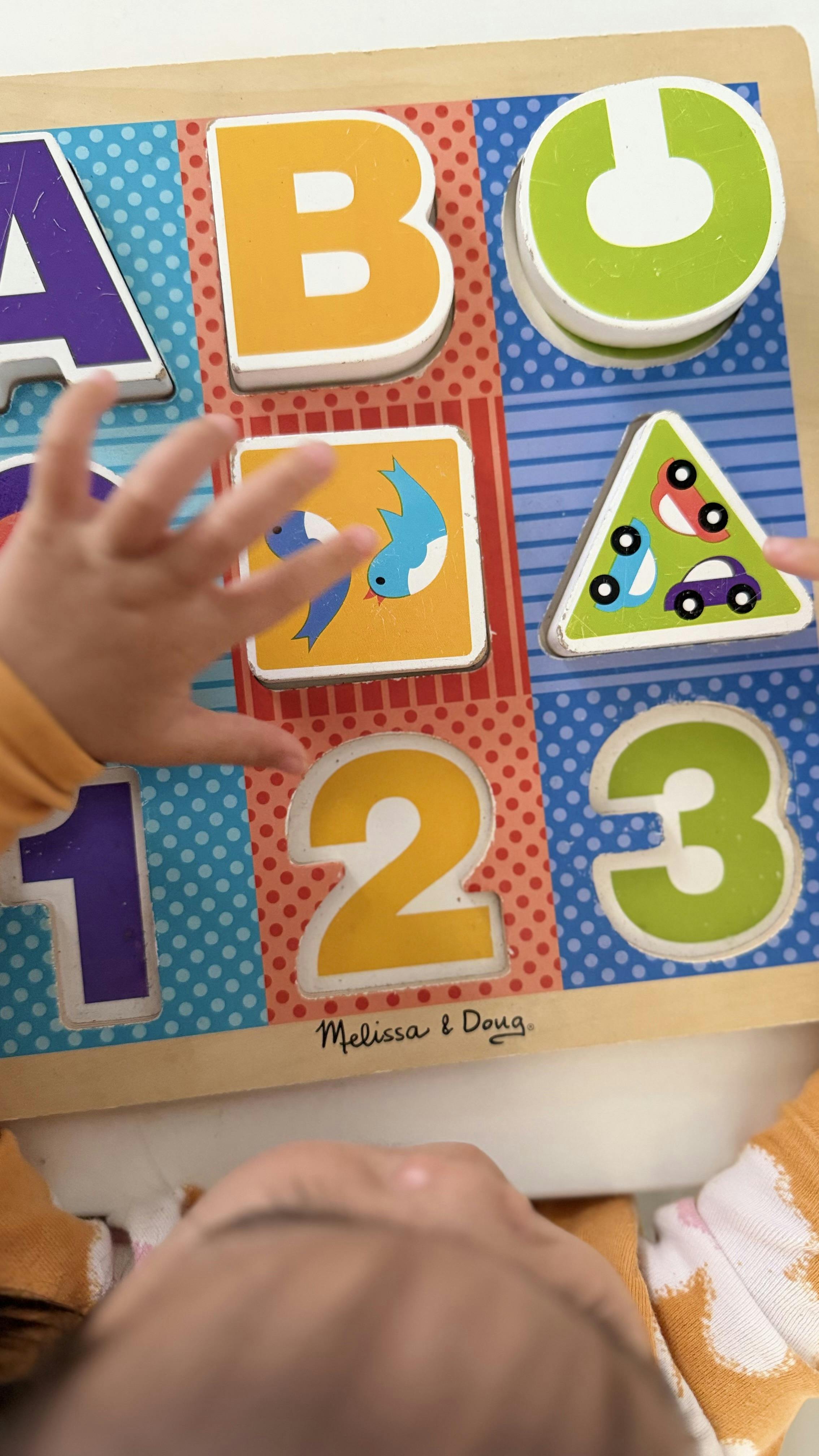 Child playing with a wooden letters and numbers puzzle