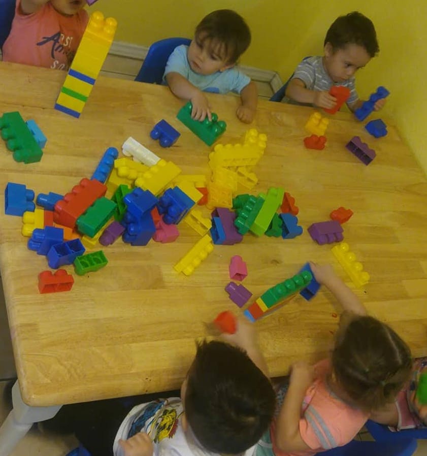 Children playing with colorful building blocks on a wooden table