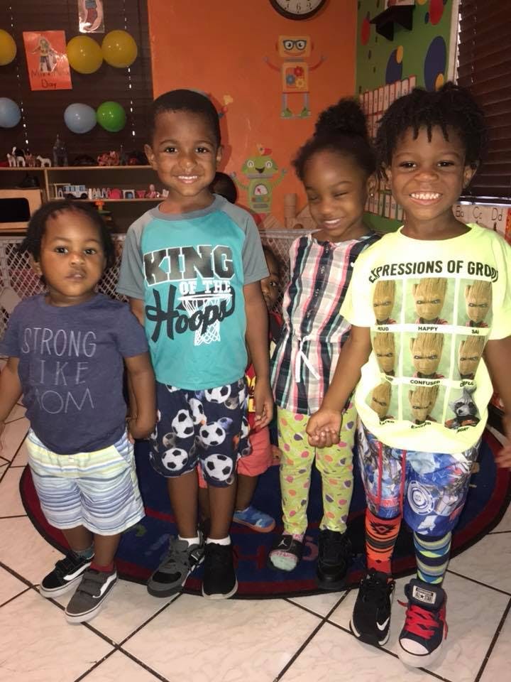 Four children standing together indoors