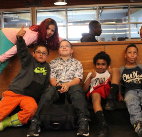 Group of children and teens posing, some giving thumbs up