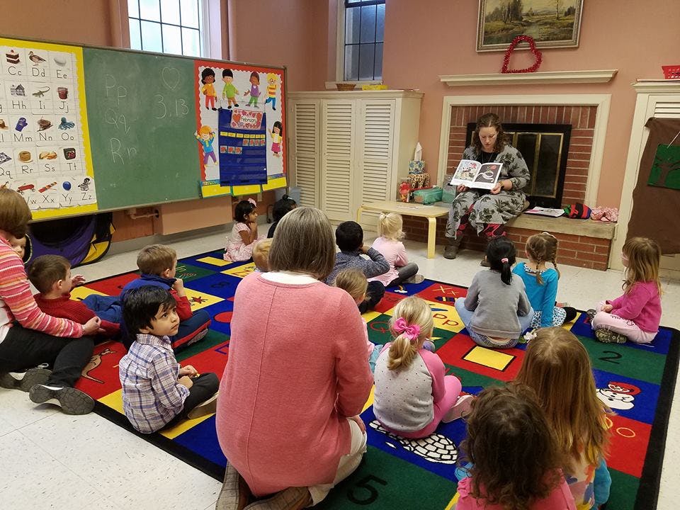 Adult reading a book to children in a classroom