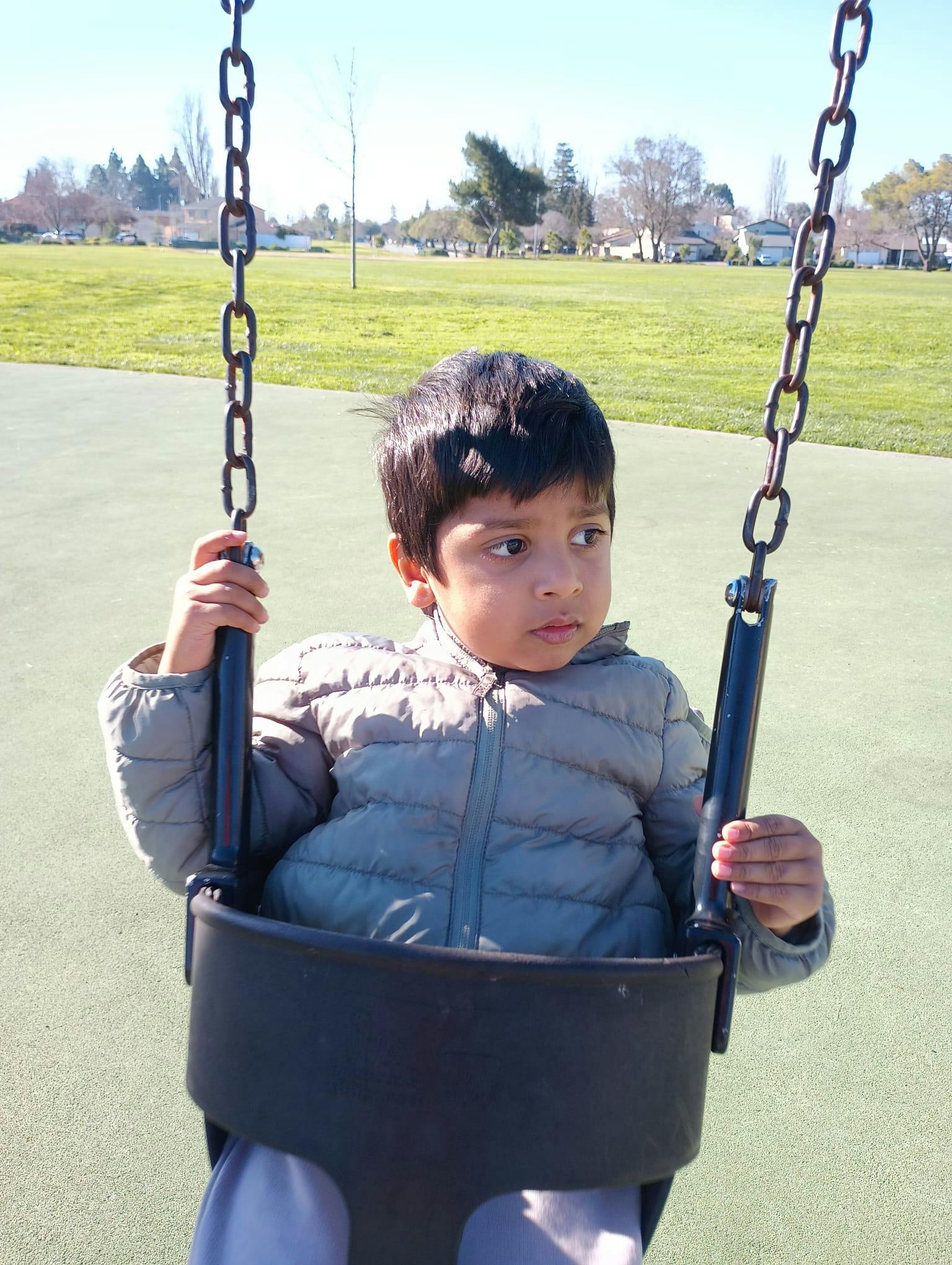 Child sitting in a bucket swing at a park