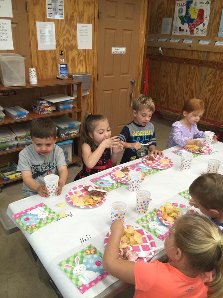 Children eating at a long table in a classroom