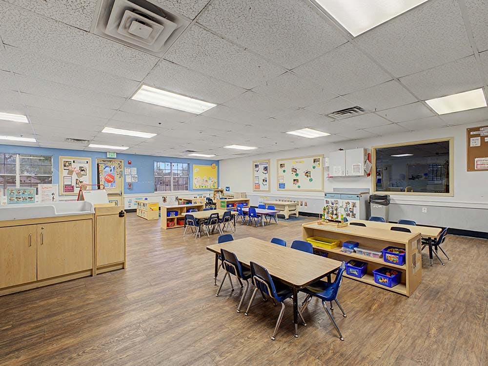 Empty preschool classroom with small tables and chairs