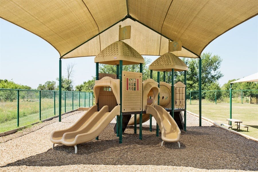 Playground with slides and climbing structures under a shade canopy
