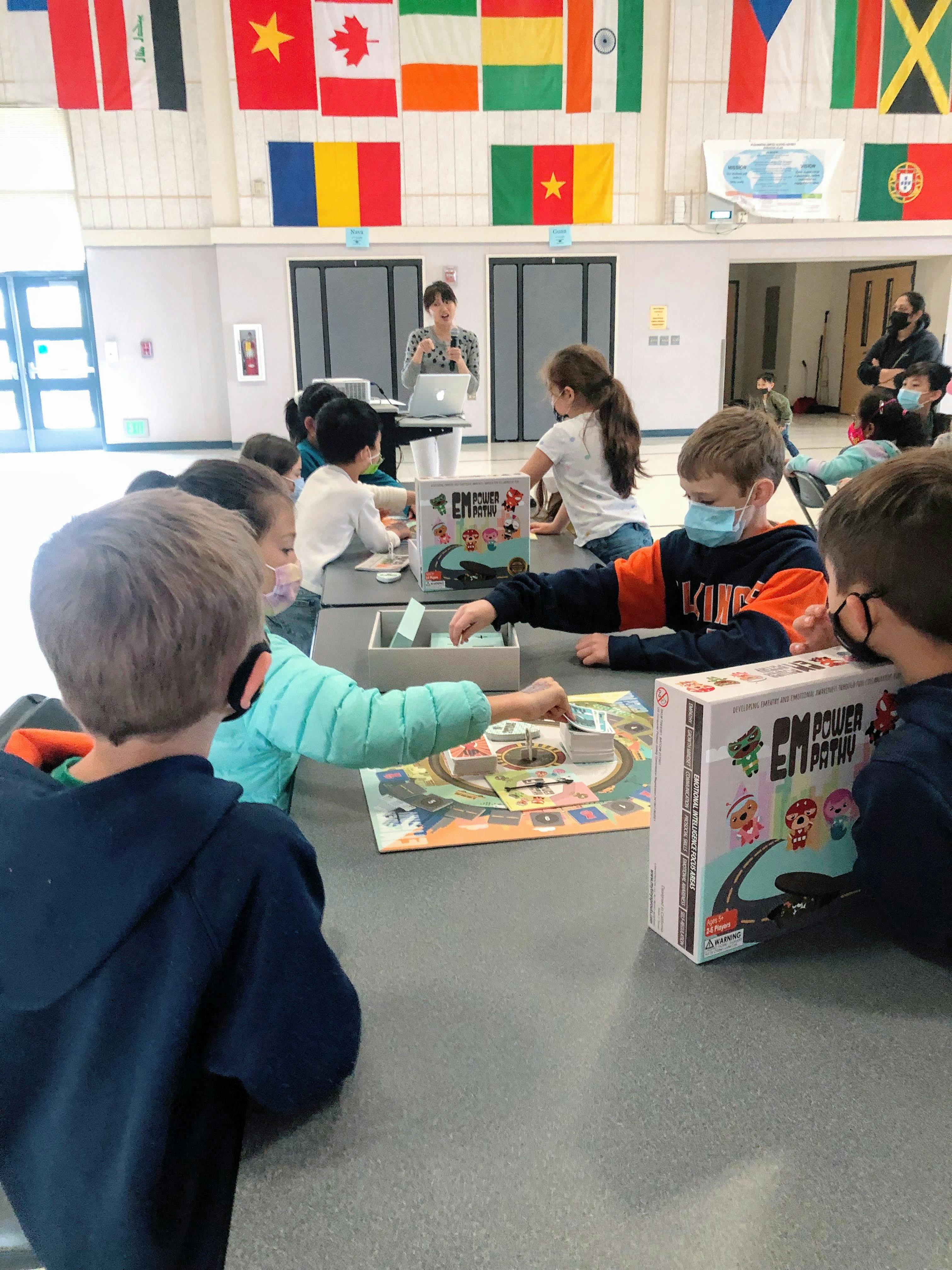 Children playing the EmPowerPathy board game in a classroom with a person teaching