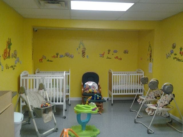Nursery room with two cribs, two infant swings, and a baby walker