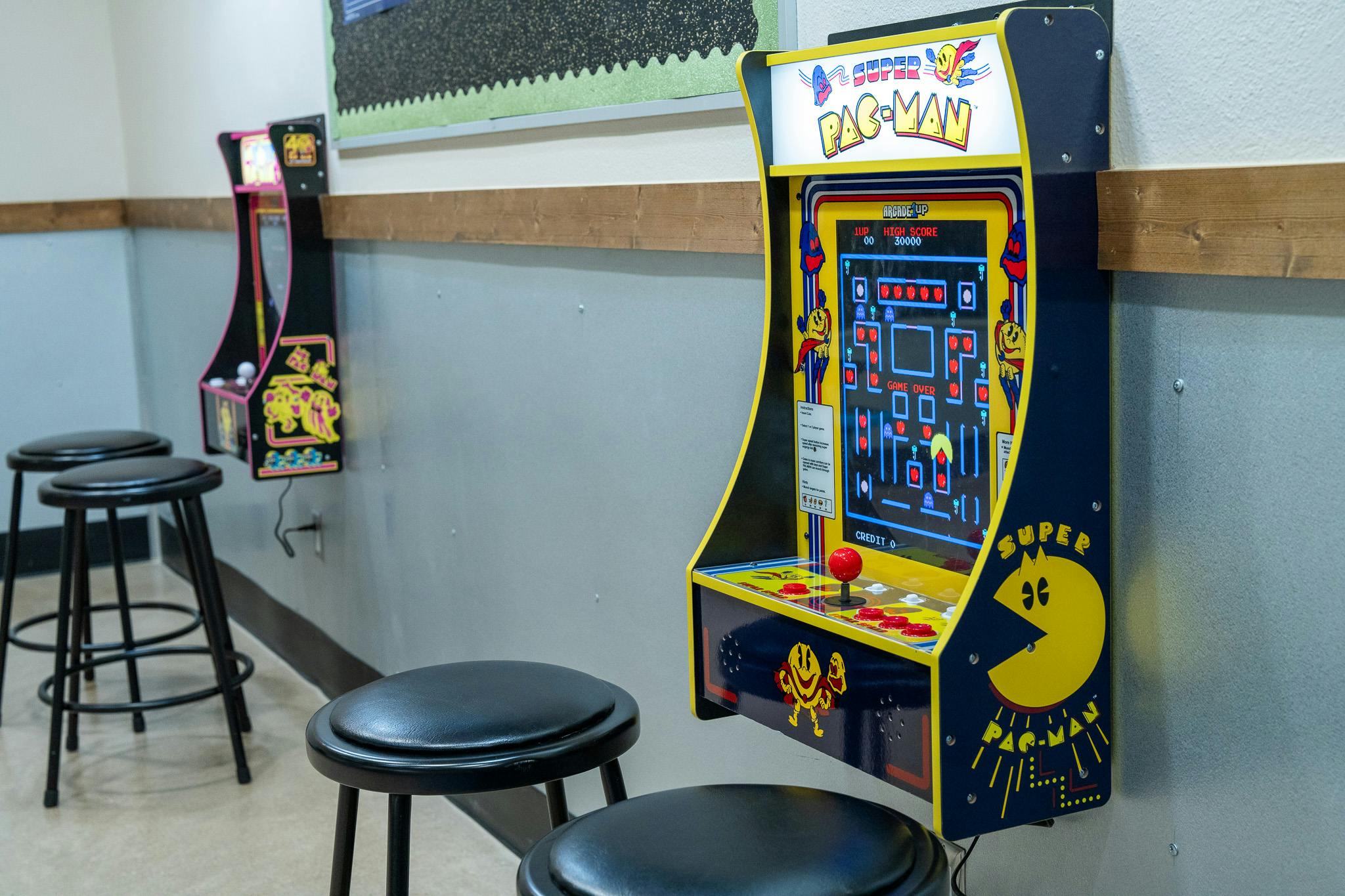 Super Pac-Man wall-mounted arcade cabinets with bar stools