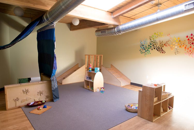 Playroom with wooden shelves, ramps, and a gray rug