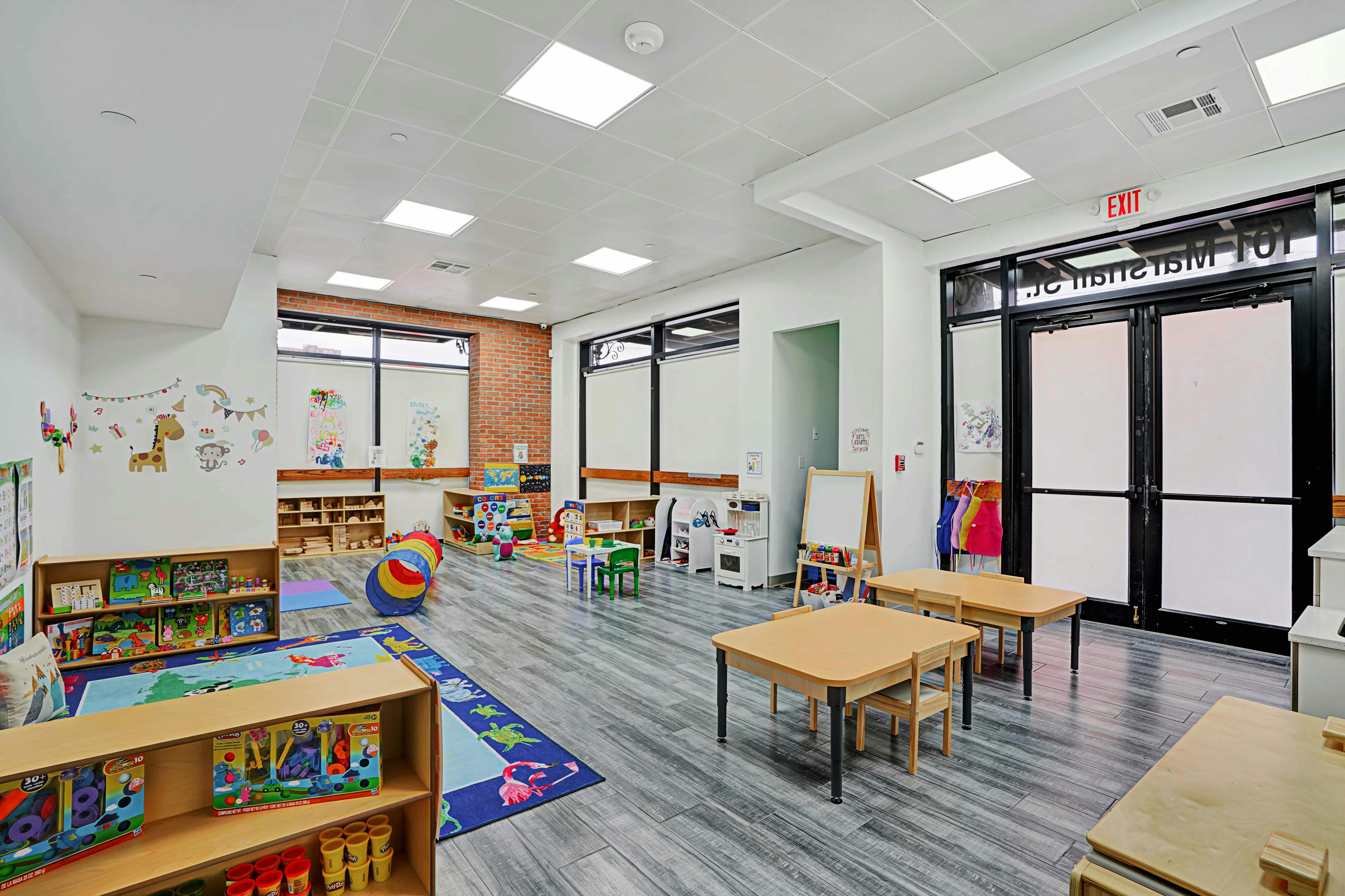 Empty classroom with small tables, chairs, and bookshelves