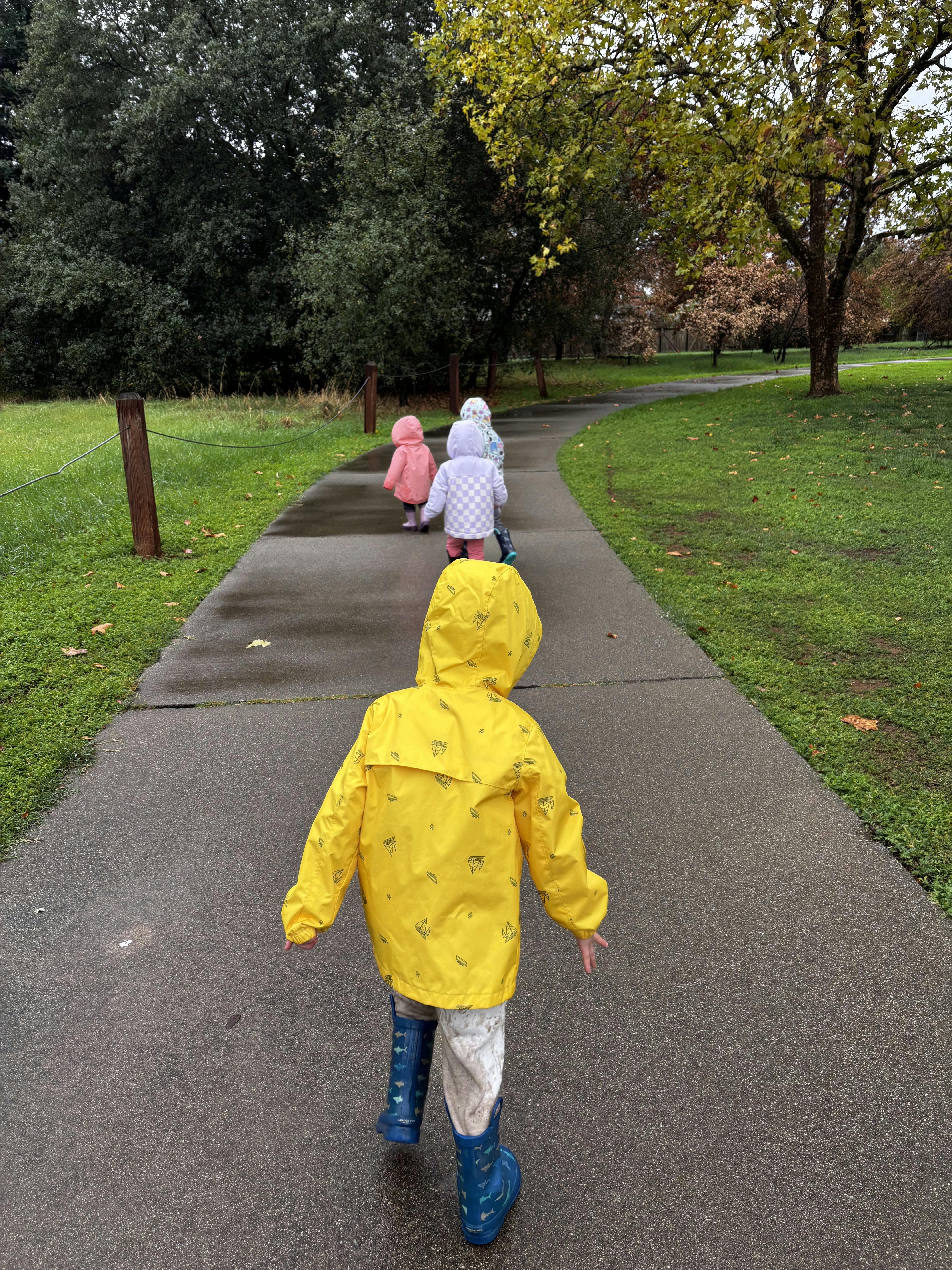 Children in rain gear walking along a park path