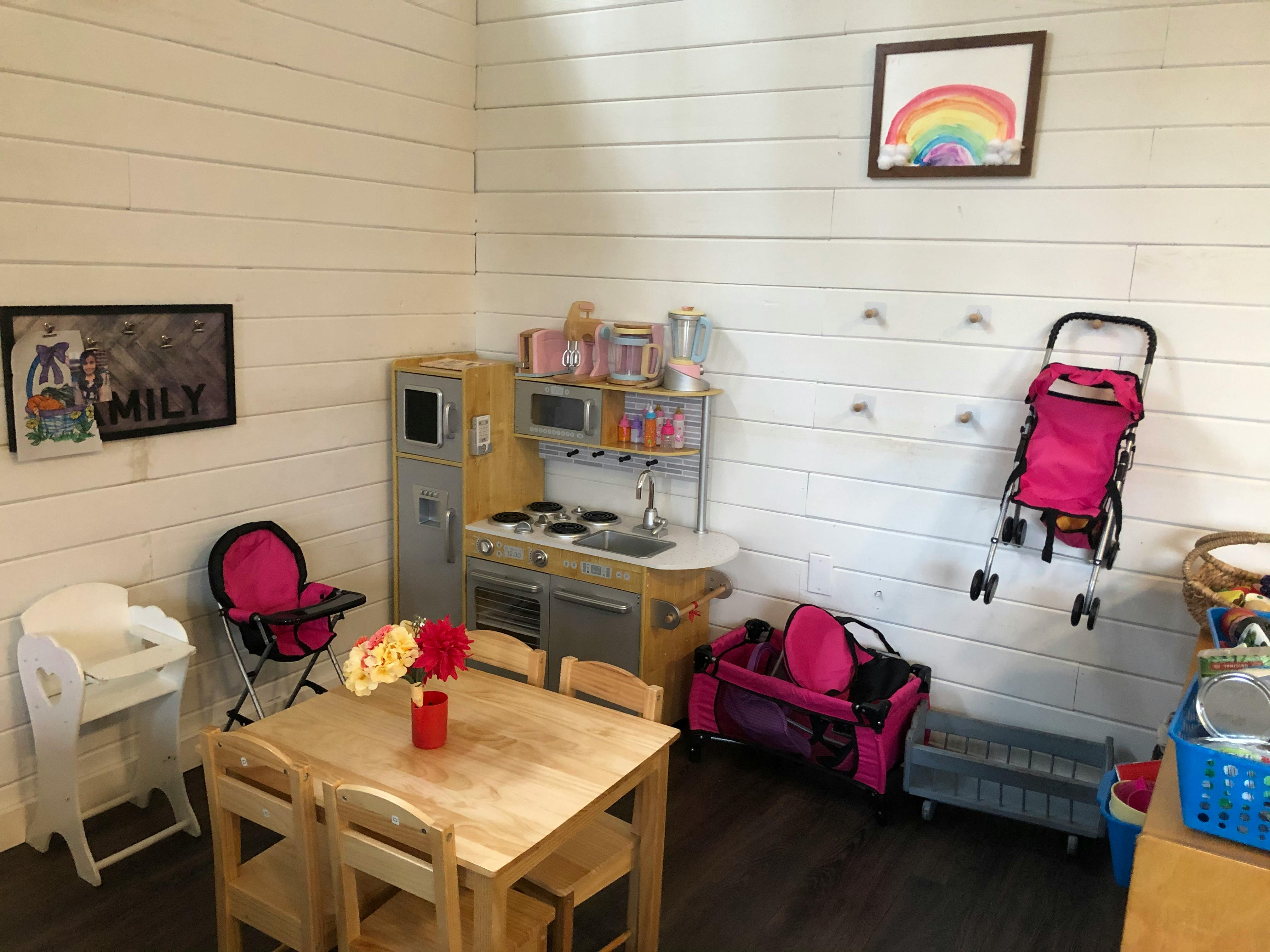 Playroom with toy kitchen, table and chairs, high chair, and stroller